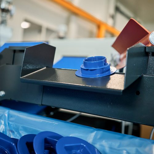 Gros plan sur des composants plastiques bleus sur la ligne de production – pièces moulées par injection.