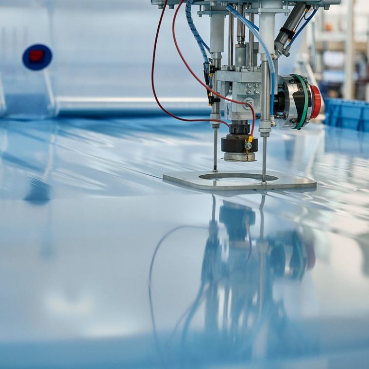 Machine industrielle pour la production d’emballages en film – gros plan sur la tête de travail au-dessus du film déployé.